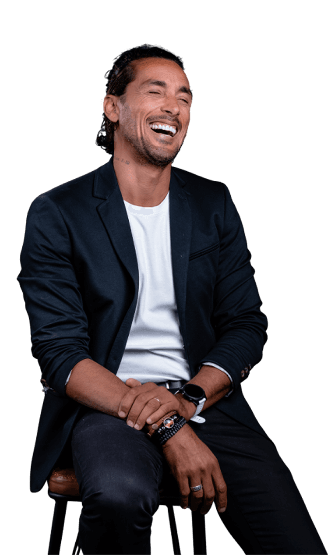 Leandro Freitas sorrindo sentado em um banco